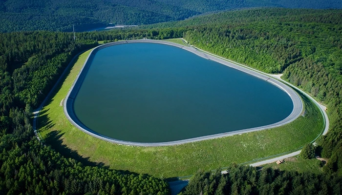 A photo of a water reservoir in a green valley