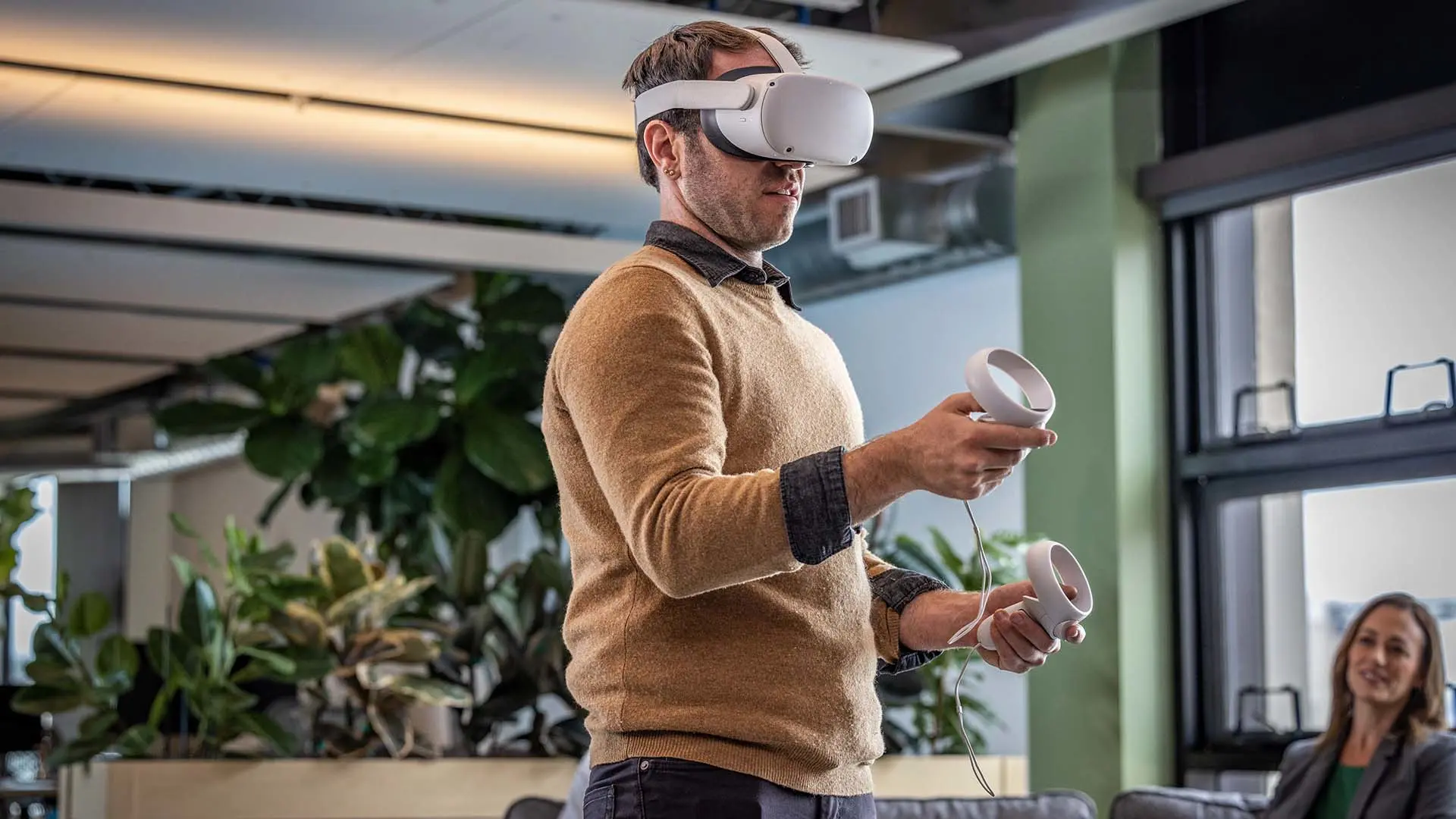 A man wearing VR glasses stands in an office. 