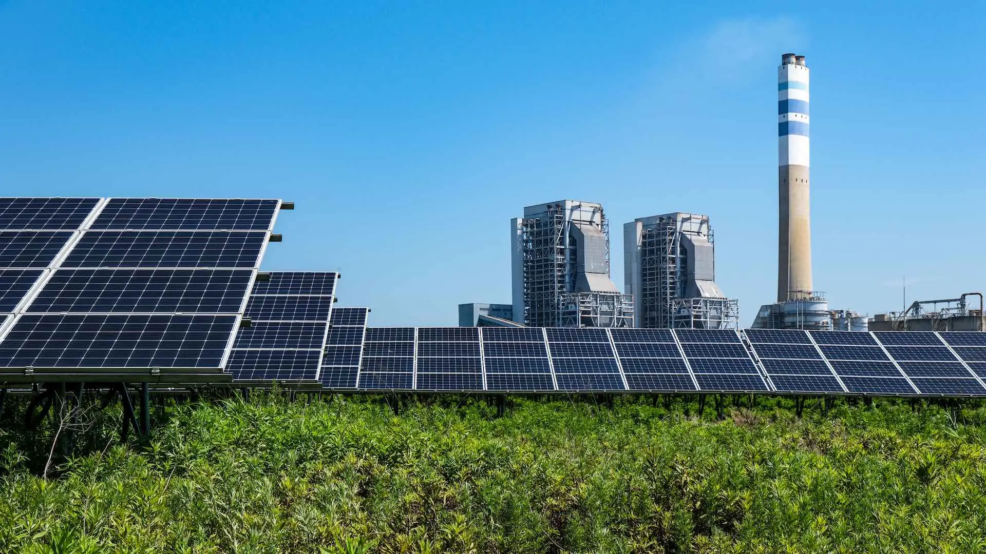 A photovoltaic power plant with thermal power plant in background
