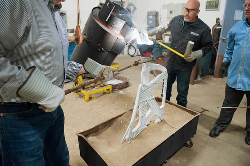 Workers pour molten magnesium into an airplane seat mold.