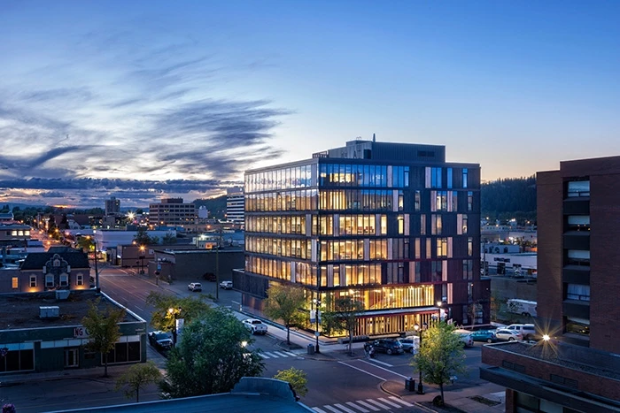 Exterior view of the Wood Innovation and Design Centre at dusk with street and sky