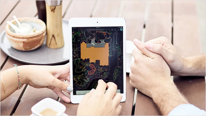 Designers gather around a tablet with a rendering onscreen.