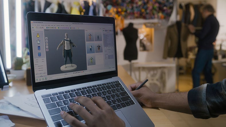 A designer creates 3D clothes on a laptop.