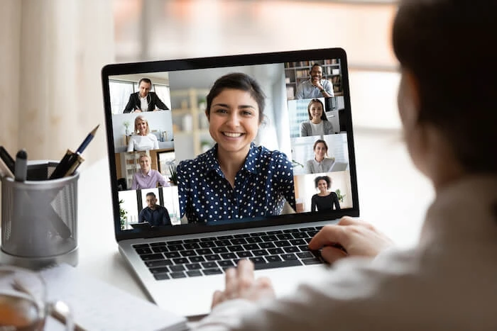 Woman works on laptop displaying the faces of her coworkers in a virtual meeting