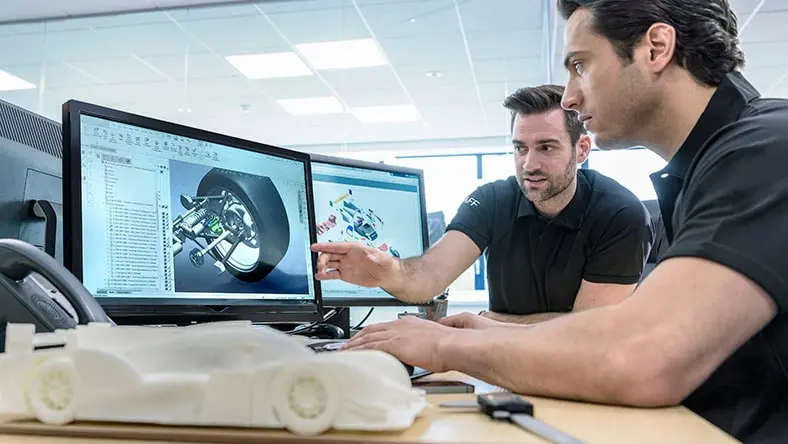 Engineers work with CAD design imagery in a racing car factory.