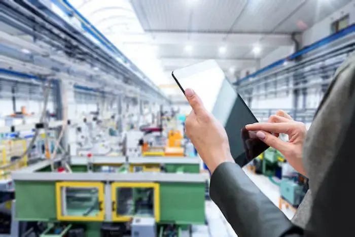 A factory worker consults a tablet on the production line.
