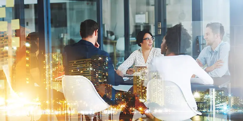 Construction company workers discuss projects around a conference room table.