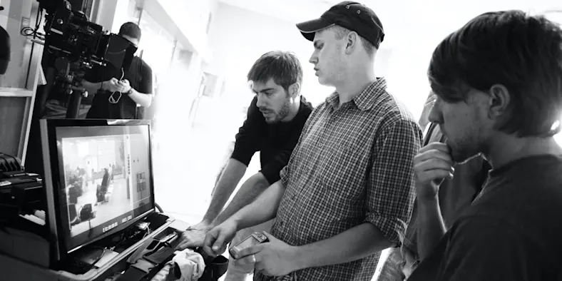 people working on a film in front of a computer