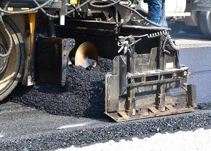 A machine lays pavement in a road