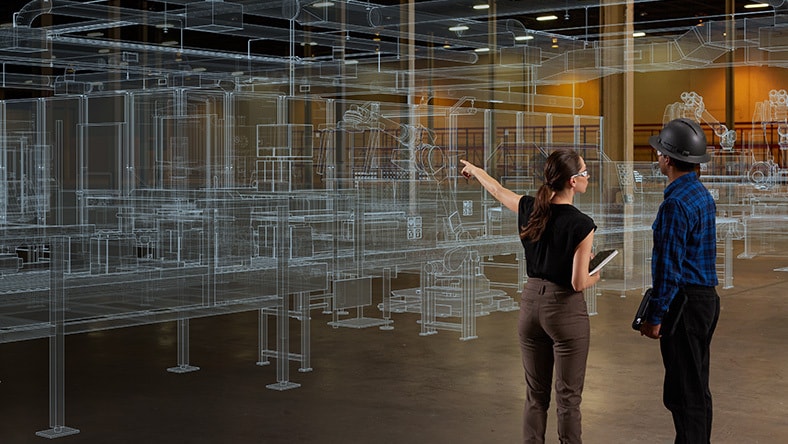 Two people review a preview of a factory layout.