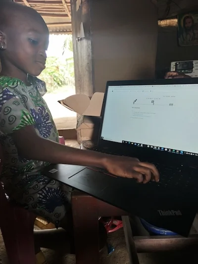 A child in Onono, Nigeria uses a computer powered by an Okra Solar mesh grid