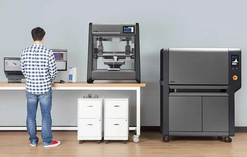 A man stands in front of a 3D printer.