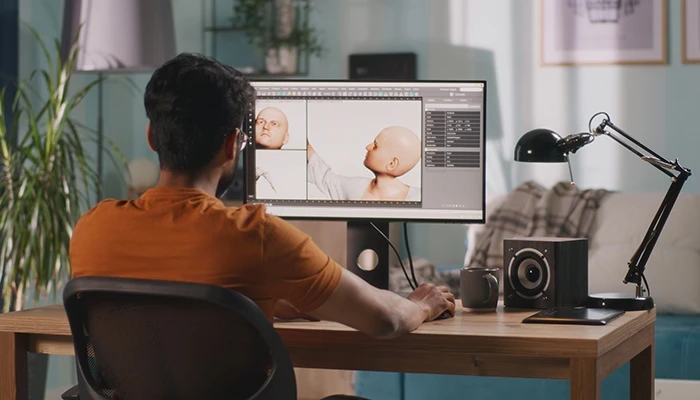 An animator sits at a computer workstation, designing a character