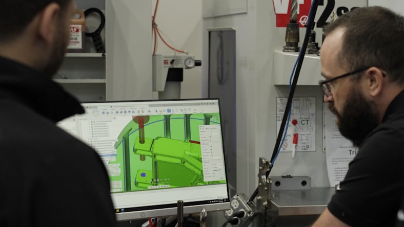 Engineers programming a mold component using Autodesk software