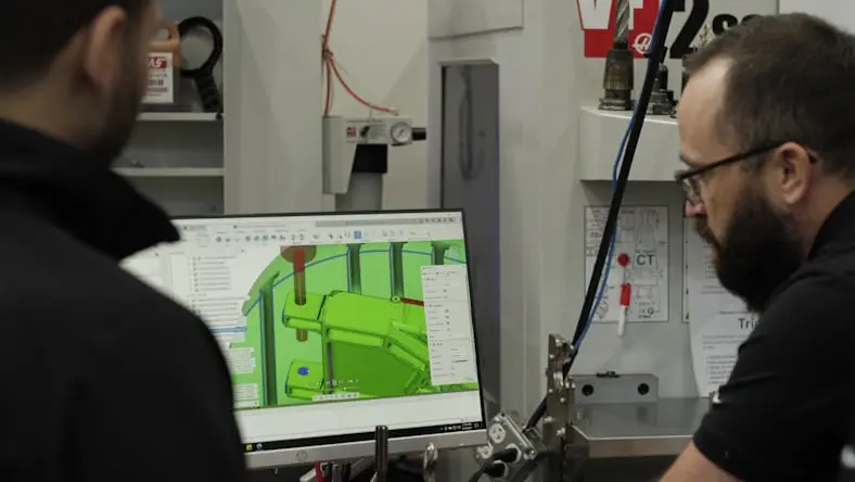 Engineers programming a mold component using Autodesk software