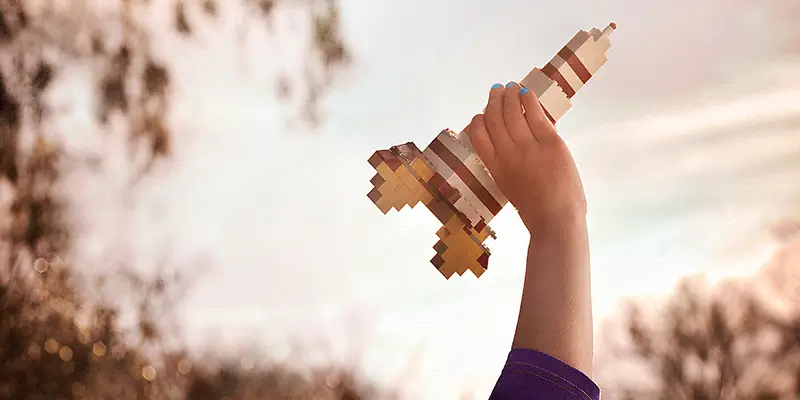 A child's hand holding toy rocket made of legos, animated booster fire