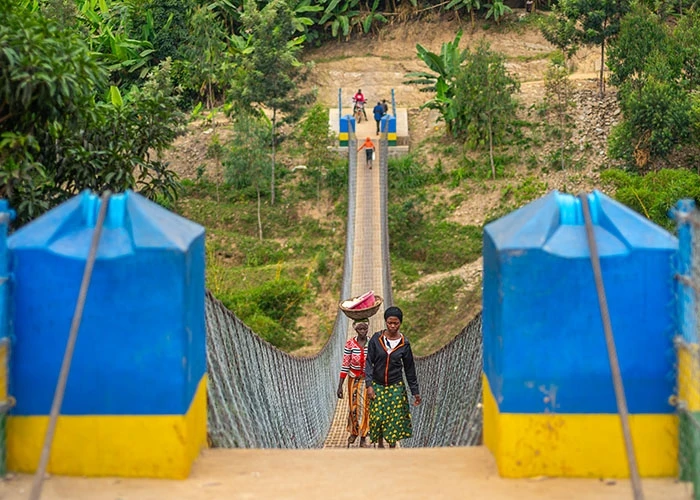 People walk across a trail bridge in rural Rwanda