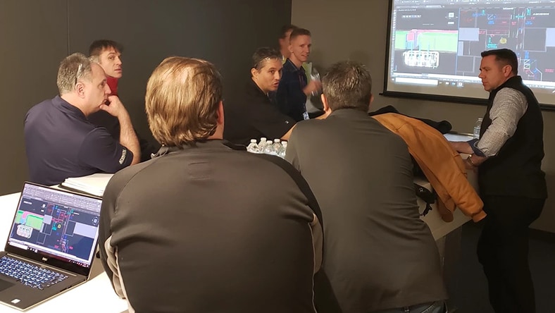 Architects consult a computer screen displaying a building design.