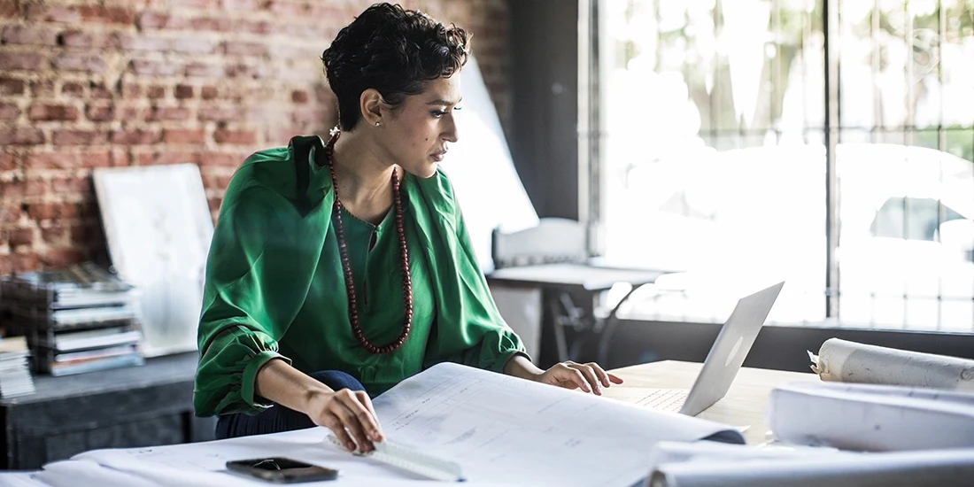 Female architect in green shirt looks at building plans