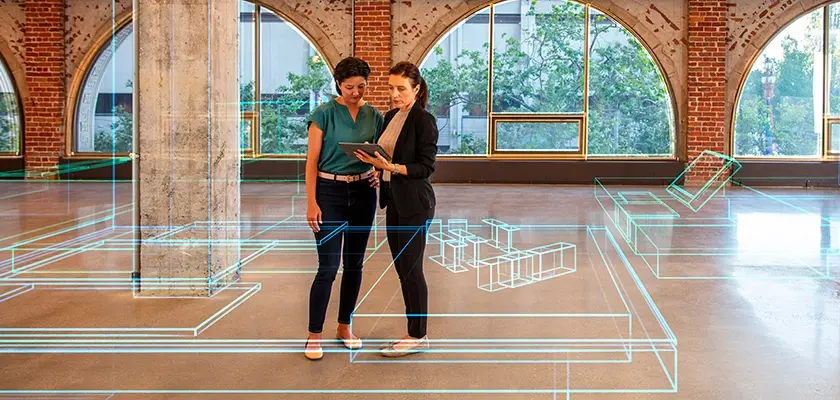 Two women looking at schematics on tablet
