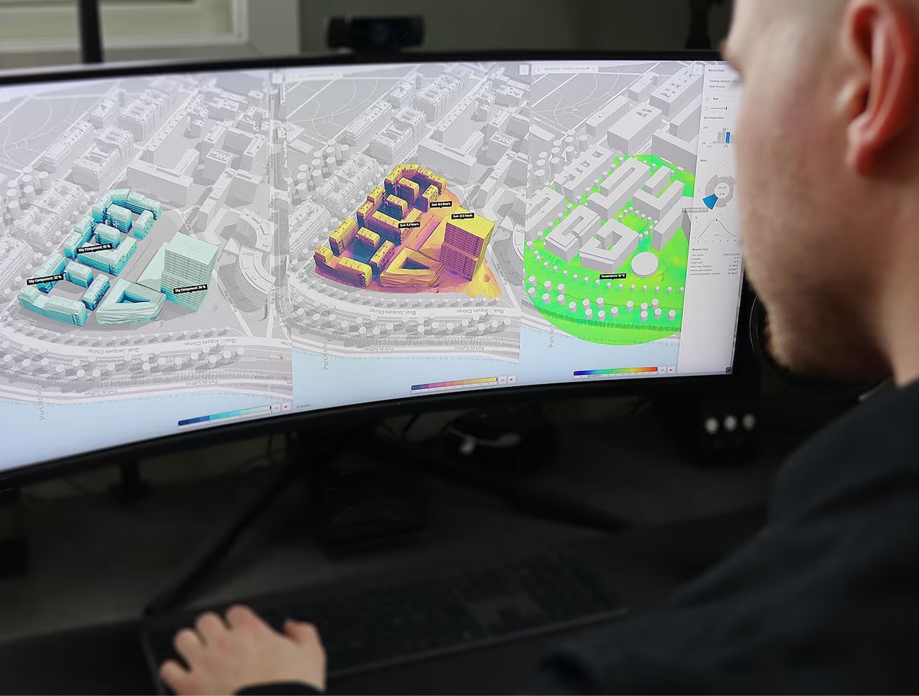 A man looks at a computer screen displaying color-coded building renderings.