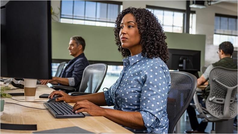 A woman works on a computer in an open office space.