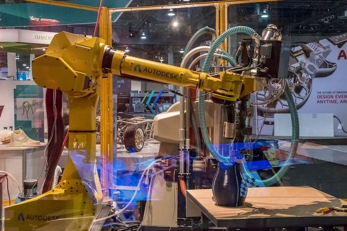 The arm of a machine 3D printing an object