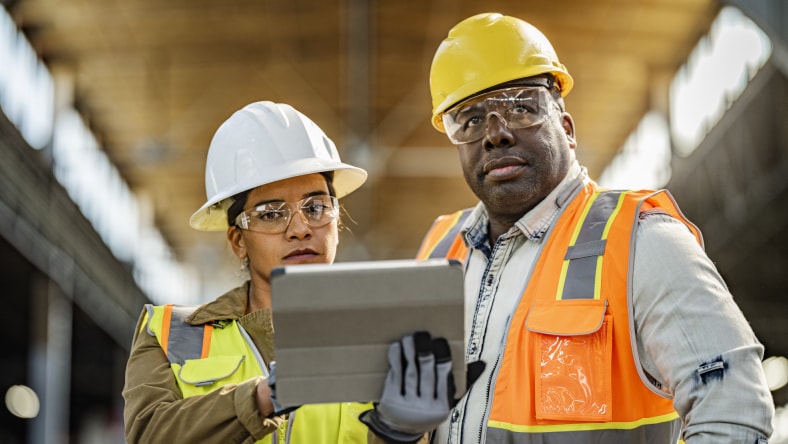 Workers viewing a digital tablet at a construction site.