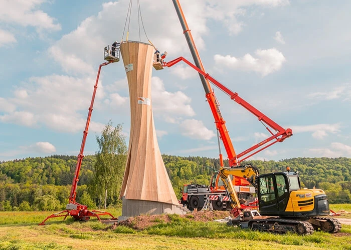 Construction crew assembles prefabricated wooden parts of Urbach Tower