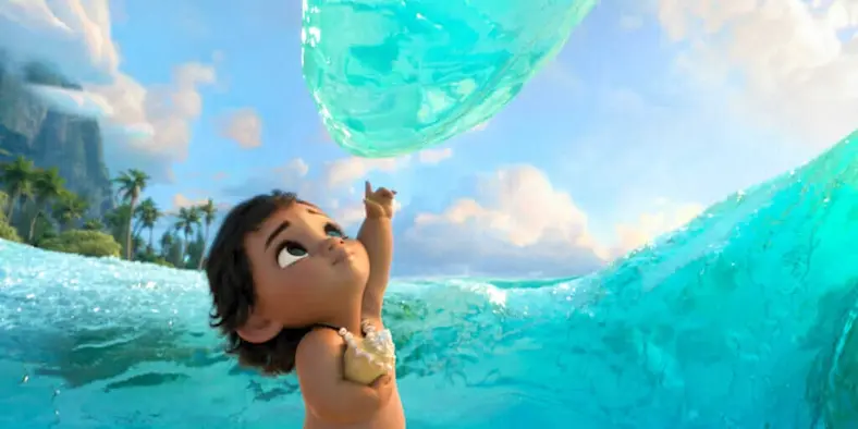 In a still from the movie Moana, a baby interacts with waves in the ocean.