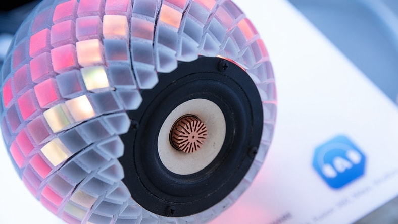 Close-up of a multicolored, 3D-printed casing on a small round speaker.