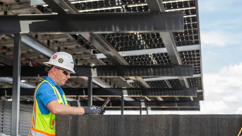 A construction worker consults a tablet on a jobsite.