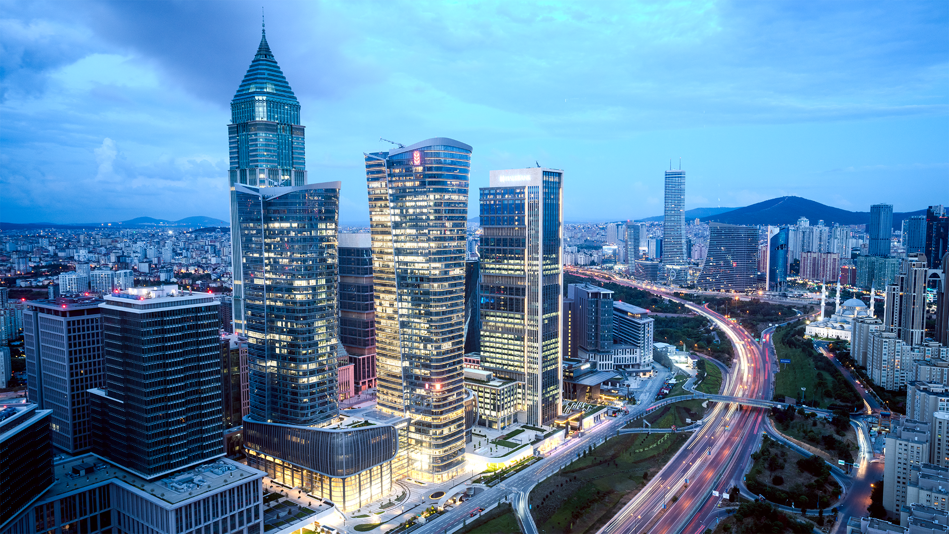 Moderne Architektur und geschäftiges Treiben: In der Dämmerung erheben sich beleuchtete Wolkenkratzer über das Stadtbild.