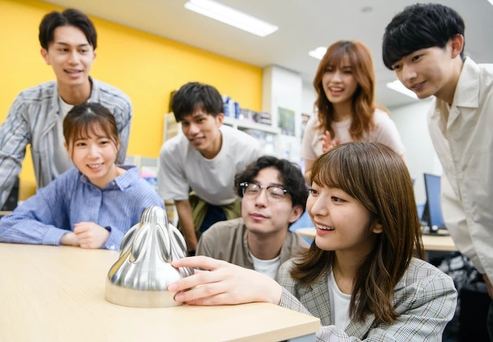 A group looks at a piece of 3D printed metal