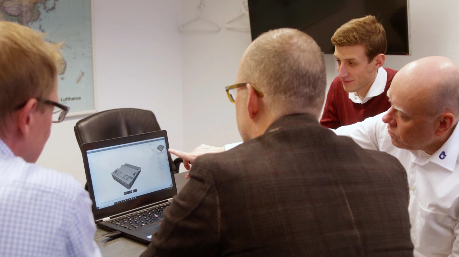 A group of people collaborating in front of a laptop screen.