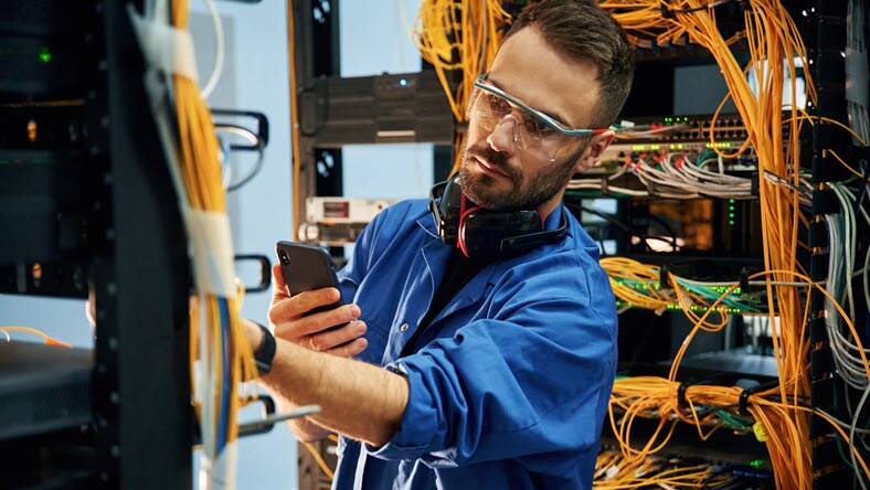 man is working with internet equipment and wires in server room
