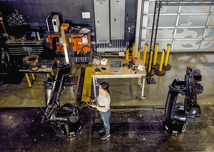 Woman on a machine shop floor working on manufacturing robots