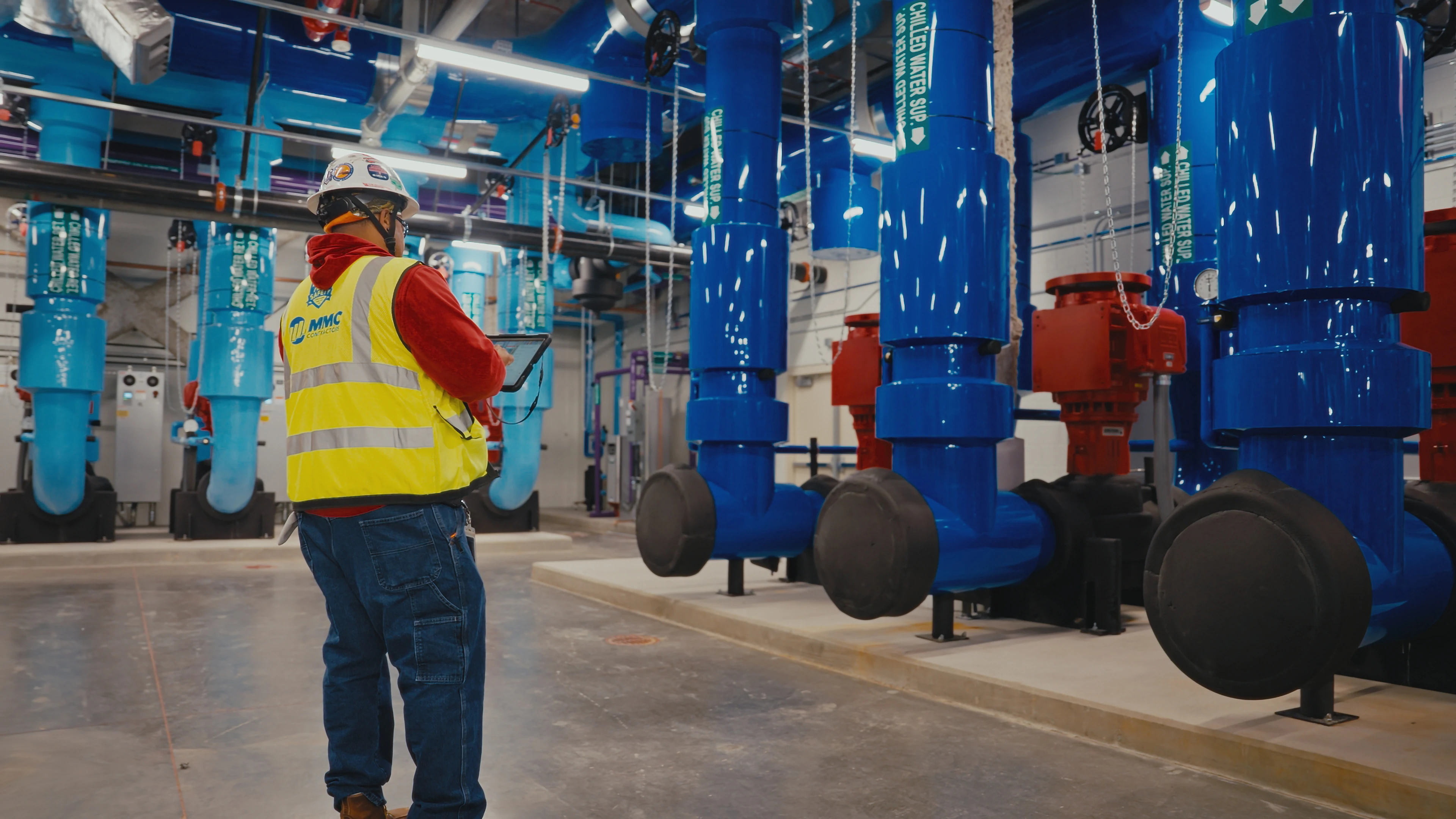 Man in construction vest and hard hat standing in front of large piping system
