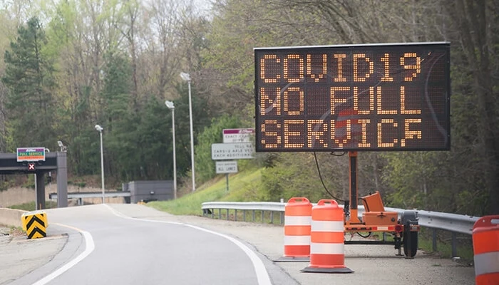 A digital road sign displaying a COVID-19 message