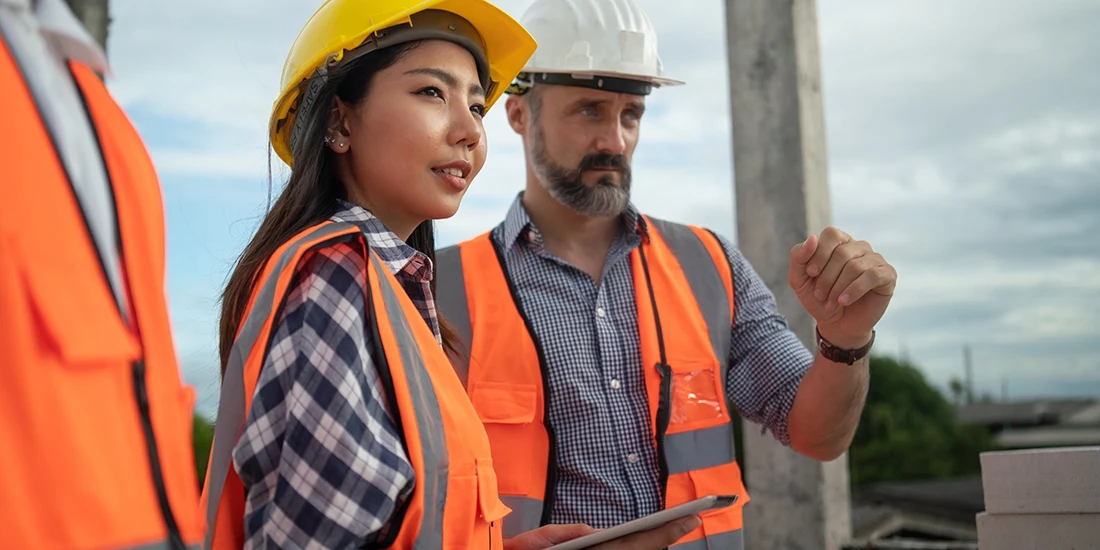 Three construction workers on a jobsite using a tablet