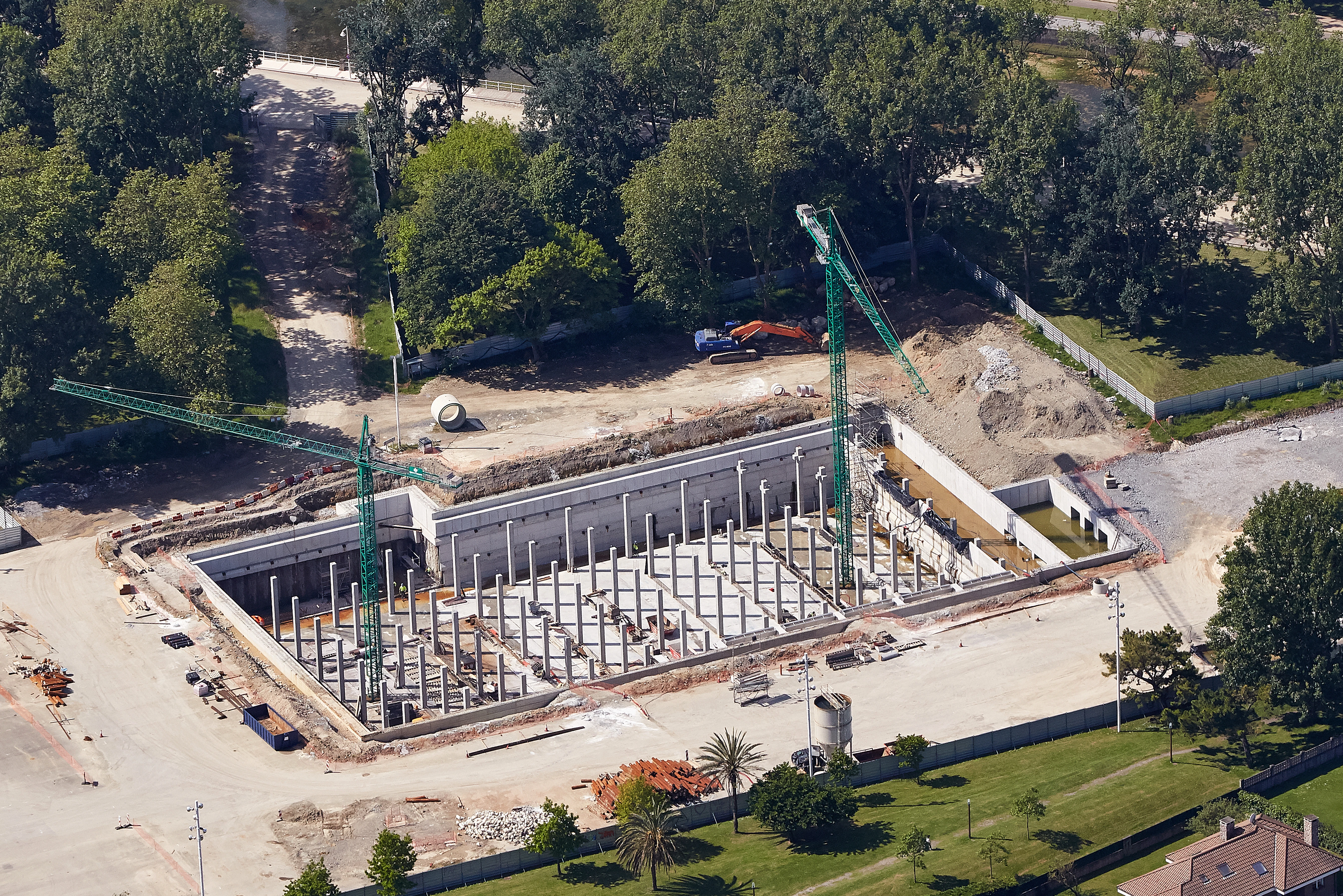 Vista aérea del tanque de tormentas Hermanos Castro en construcción en Gijón, mostrando la estructura de hormigón armado, los pilares interiores de soporte y los trabajos de obra civil en curso.
