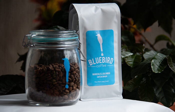 Bluebird bag of coffee beans and coffee beans in a glass jar