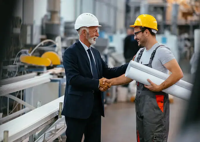 Spie batignolles executive and construction worker shake hands on a job site.