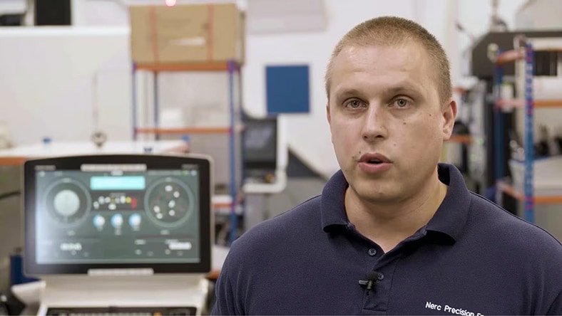 A man talks in a machine shop.