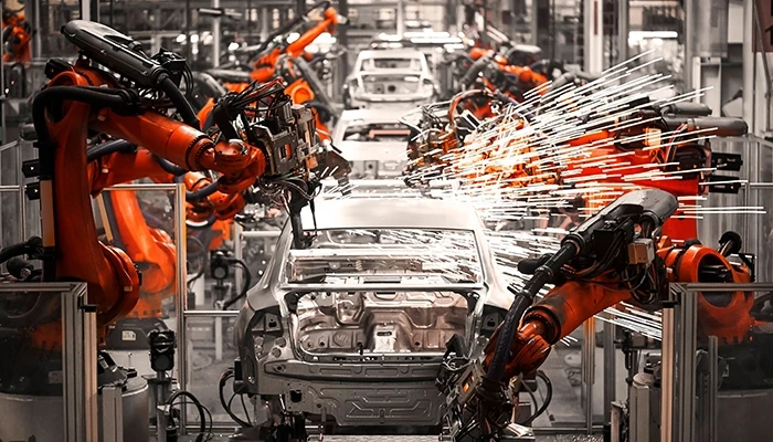 Large industrial robots work on an automotive assembly line