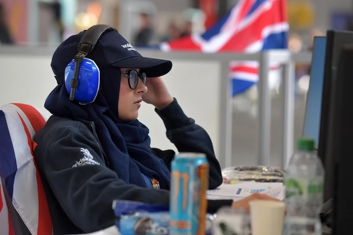 A woman wearing hearing protection looks at a computer monitor.