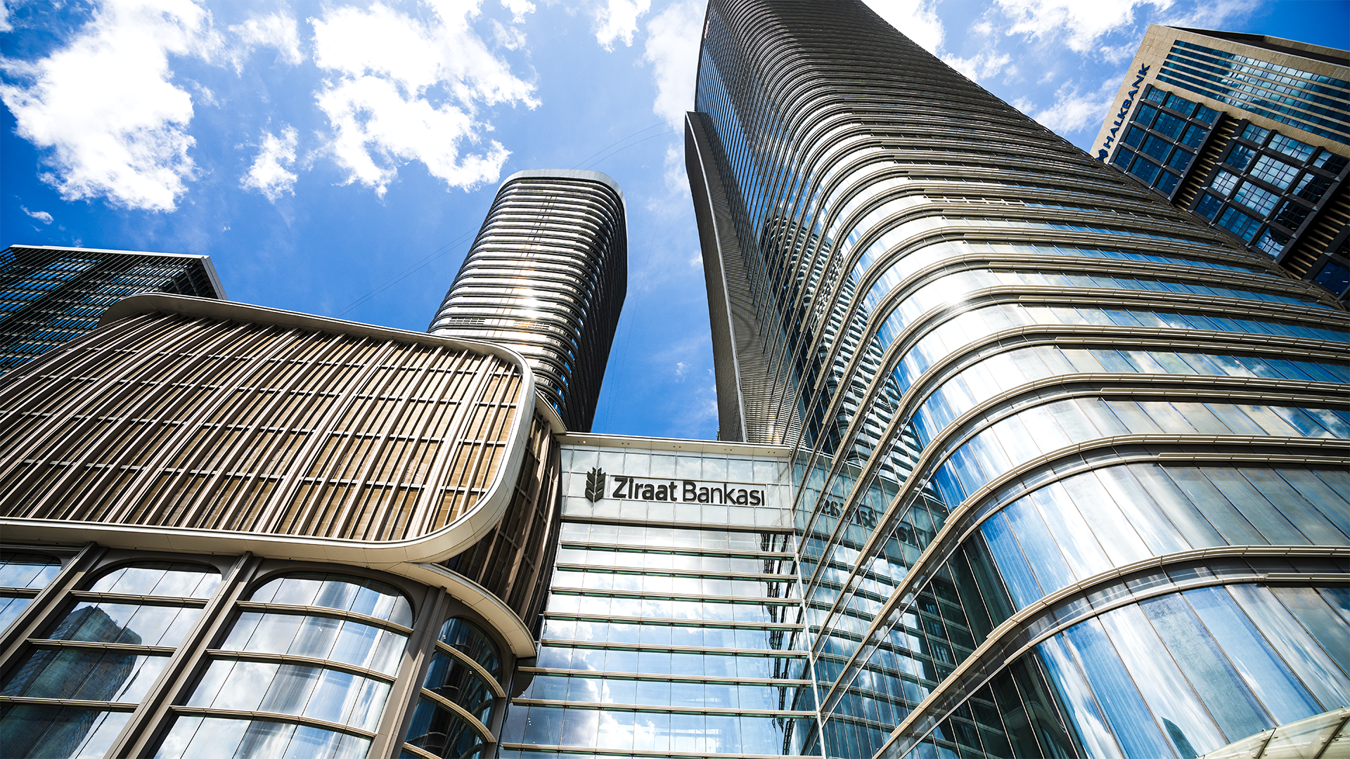 Glass-clad towers reflect the blue sky, highlighting curved facades and contemporary design.
