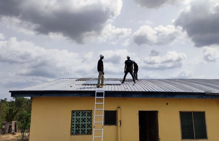 Trabajadores en Omolege, Nigeria, instalan paneles de una red en malla de Okra Solar.