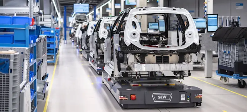 Electric car components being transported across a factory floor