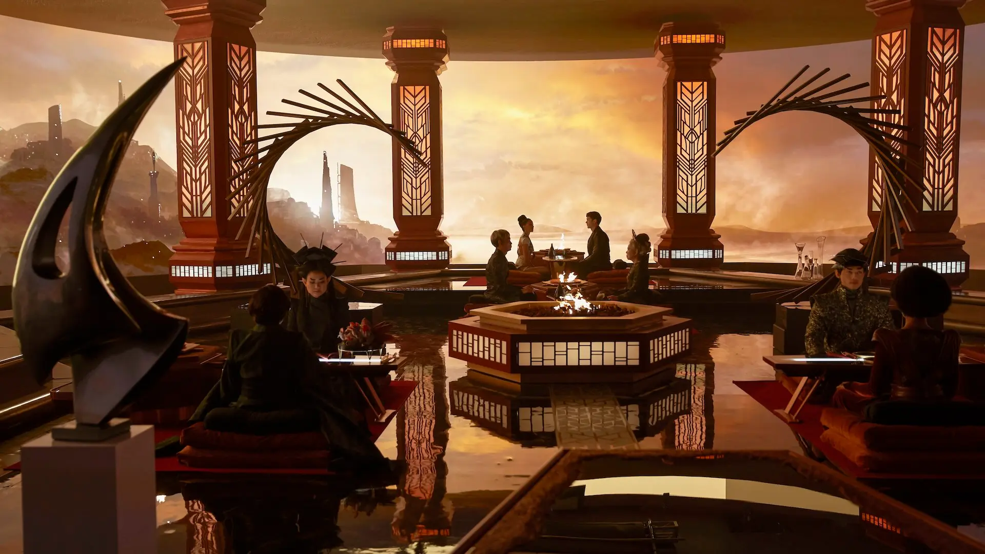 A scene from season 1 of Star Trek: Strange New Worlds shows actors dressed as Vulcans sitting in an elegant restaurant with an alien landscape visible through the large windows.